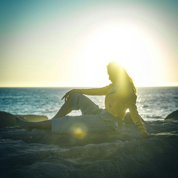 Person stretching outdoors during a beautiful sunrise, silhouette style.