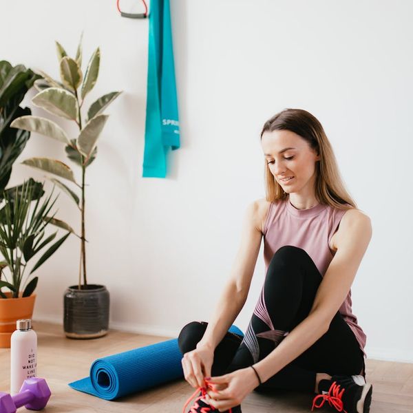 Yoga mat, water bottle, and a small towel neatly arranged on a wooden floor.